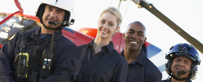 Four emergency medical responders stand next to a helicopter.