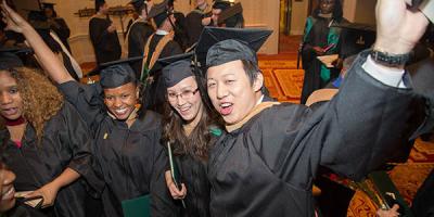 Point Park master's degree recipients shout and wave their hands in celebration after participating in graduate hooding on April 27, 2014, at the Wyndham Grand Hotel in Pittsburgh. | Photo by John Altdorfer