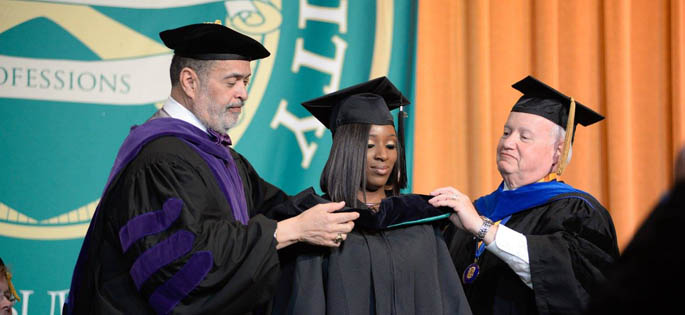 Pictured are Professors Gregory Rogers, J.D., and Richard Linzer, J.D., hooding a graduate student at Point Park's 2016 Hooding Ceremony. | Photo by Chris Rolinson