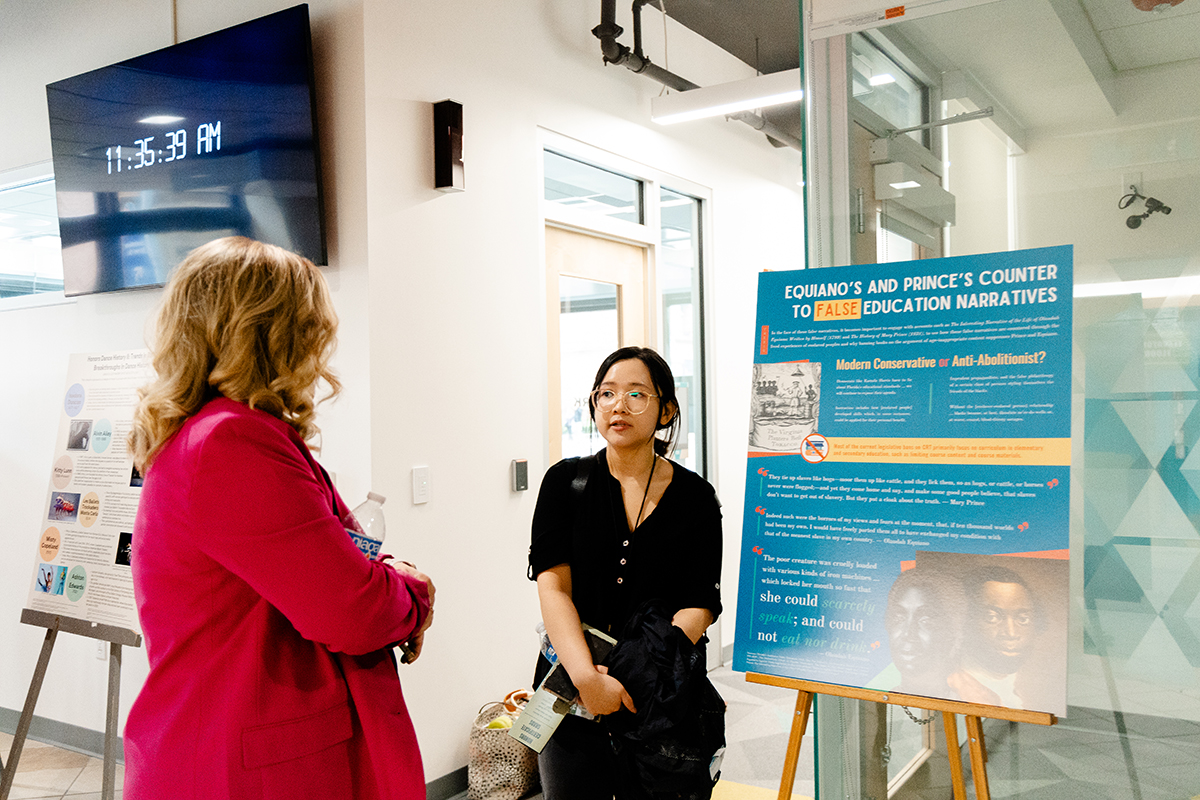 Pictured is student Kelly Le, right, talking to Professor Jessica McCort, Ph.D., about her research at the Literature, Culture & Society and Honors Program Symposium. Photo by Ethan Stoner.