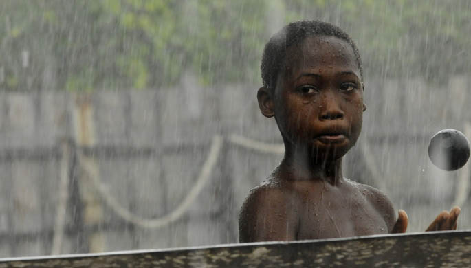 A young boy in Guyana plays with a cricket ball in the rain. | Photo by Kristopher Radder