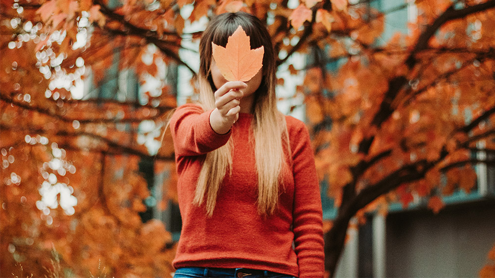 Student posing with fall leaves.