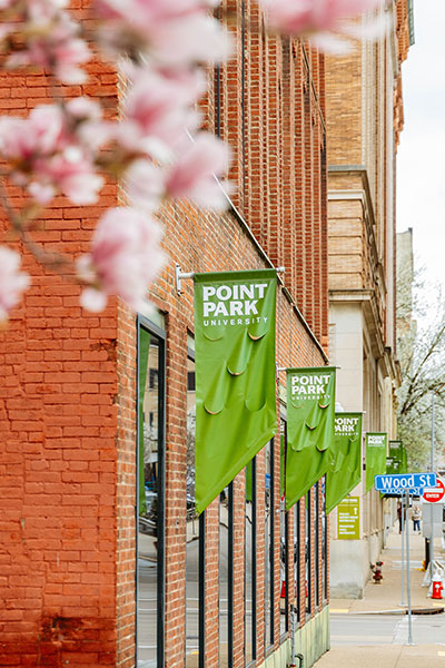 Green banners with the university logo outside Bison Bites and Brew, with cherry blossoms in the foreground