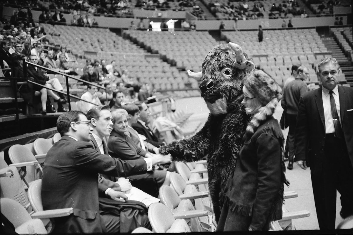 A bison mascot shakes hands with a man