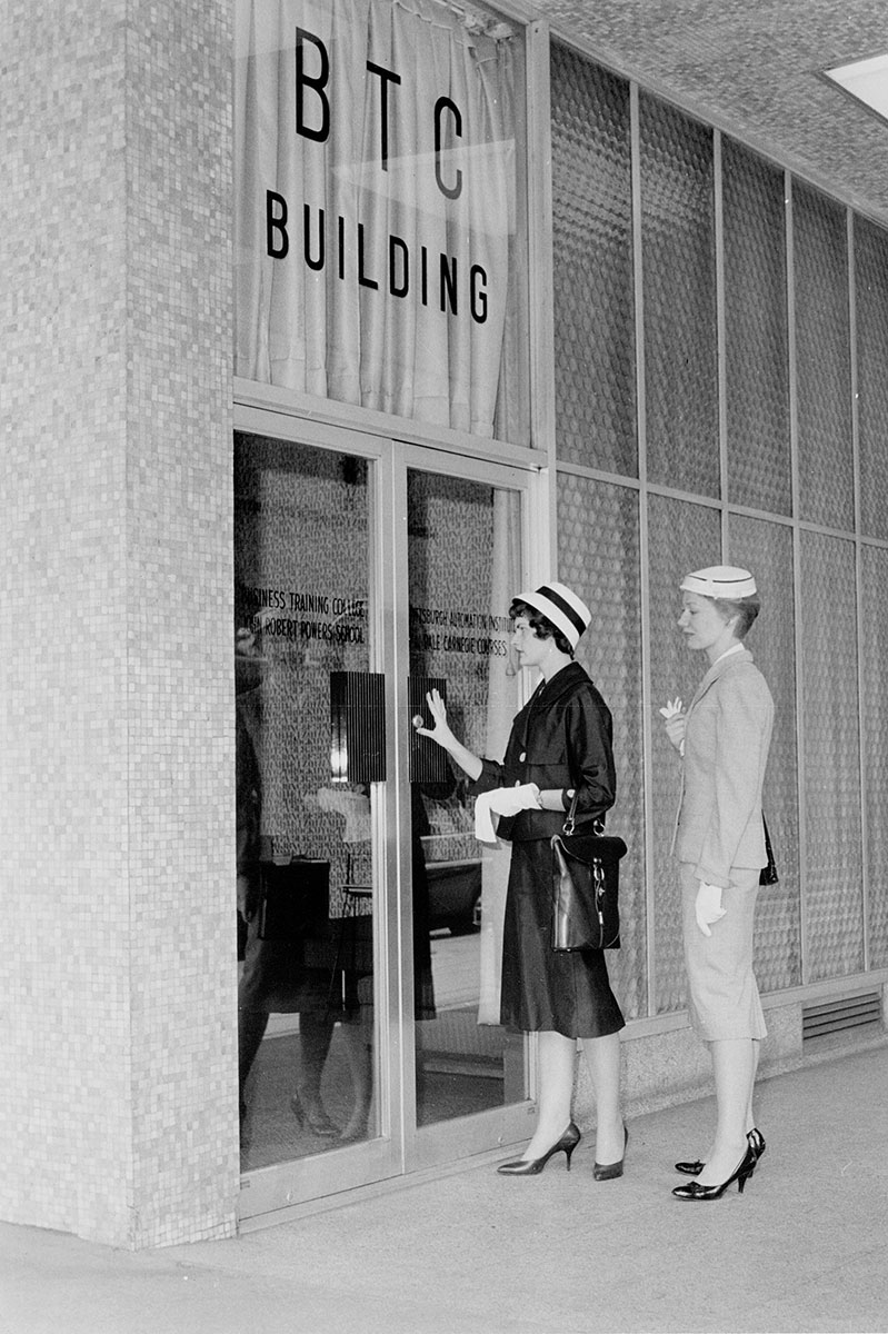 Two women stand outside the Business Technical College door