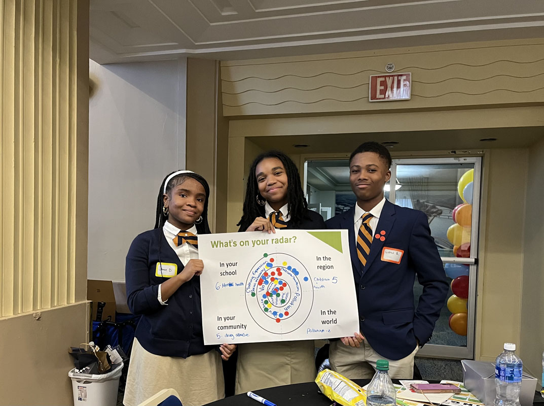 Three students hold up a sign.