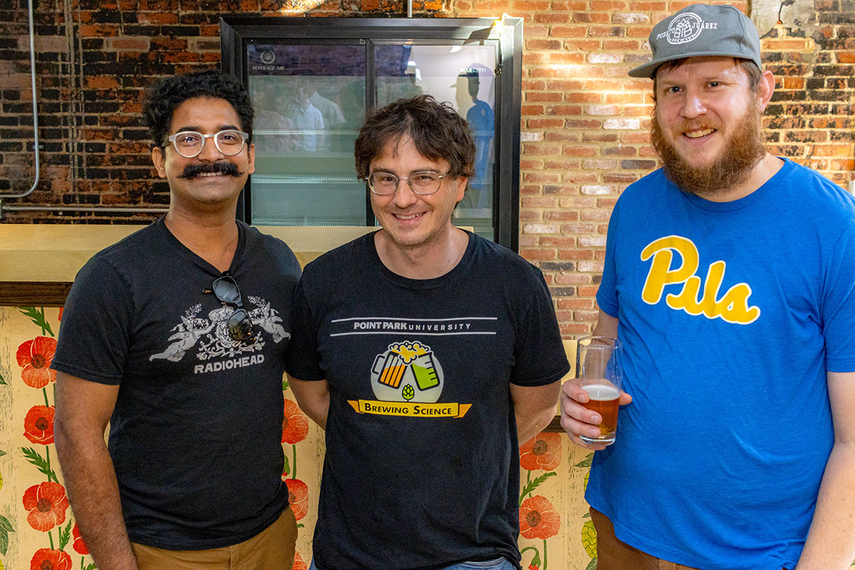 Three men smile