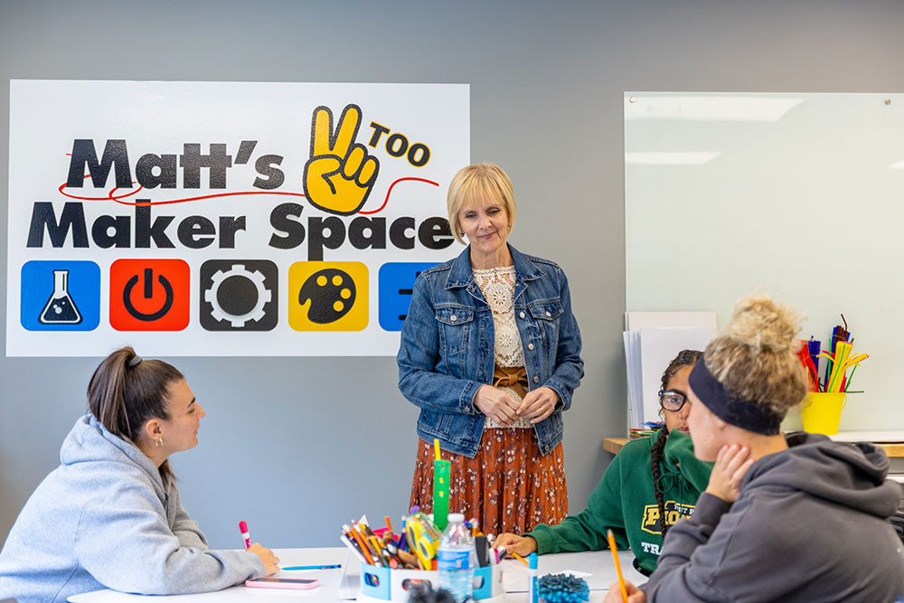Christal Edmunds oversees three students working at a table.