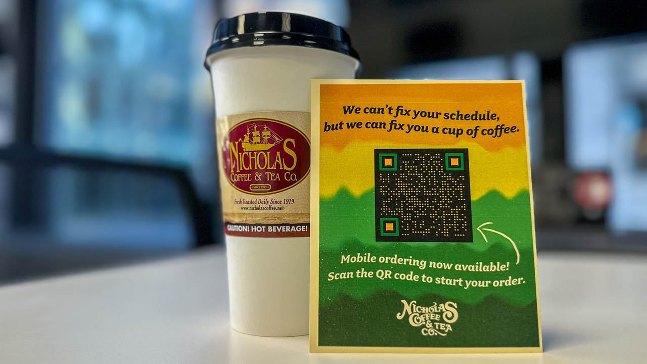 A coffee cup from Nicholas Coffee sits on a desk in Point Park University's West Penn building. The advertisement and QR code to mobile order were distributed at several parts of campus earlier this semester.