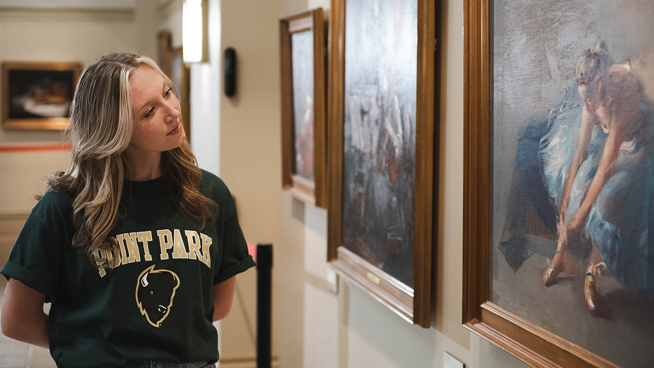 A student looking at artwork in the GRW Performance Center. 