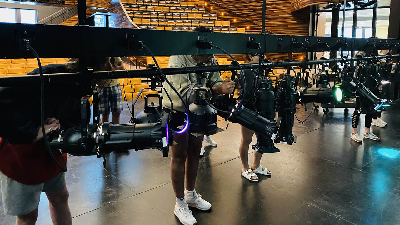 Students work on a lighting grid in the PNC Theatre.