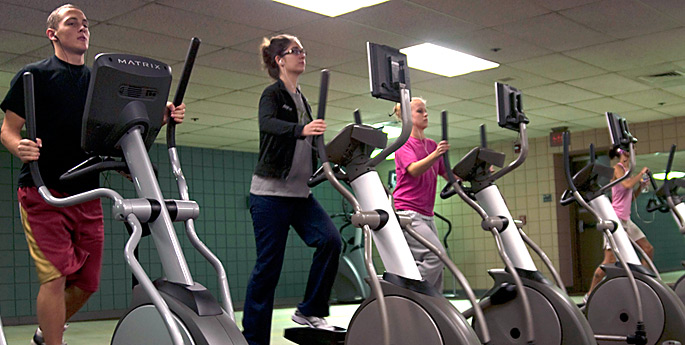 Students on elliptical machines in the fitness center.
