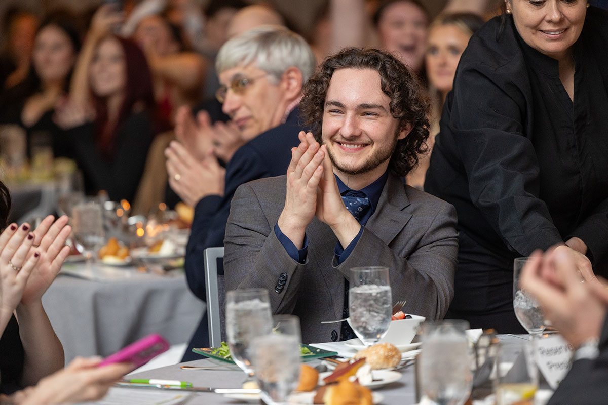 A male student at a table claps.