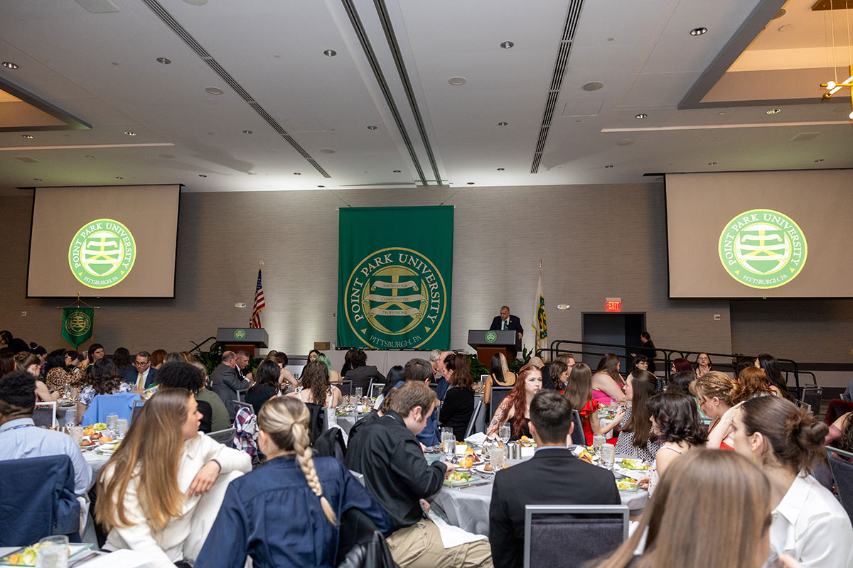 A wide angle shot of a room full of people sitting at tables.