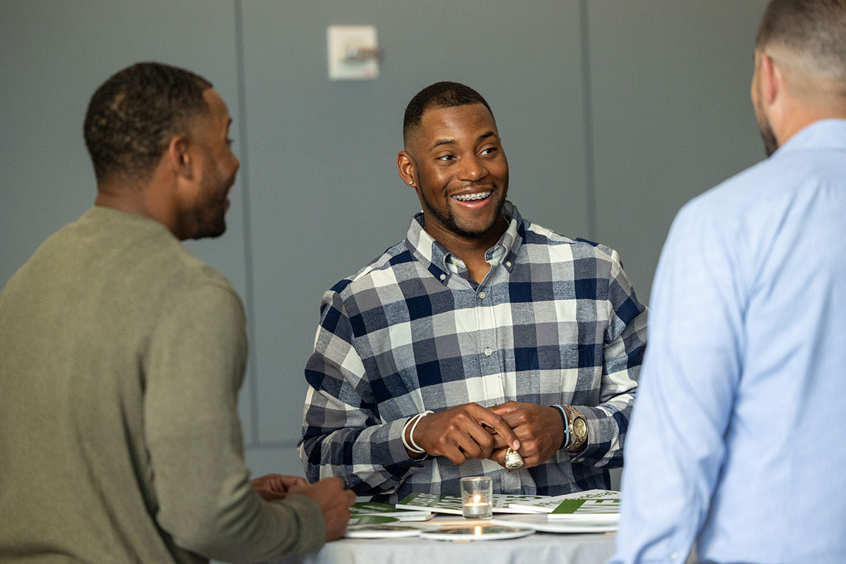 Students standing around a high-top table talk.