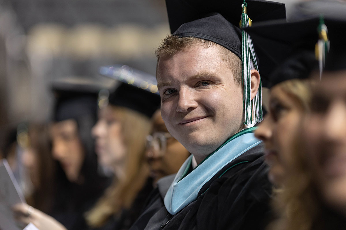 A graduate smiles at the camera