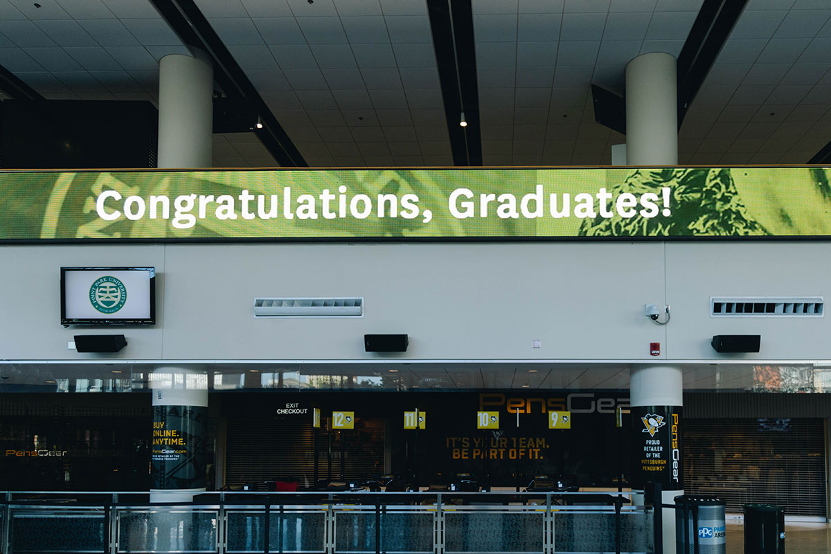 A sign inside the arena reads "Congratulations Graduates"