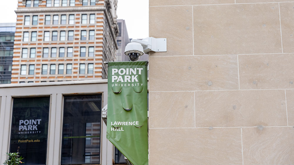 A security camera is mounted on the corner of Lawrence Hall.