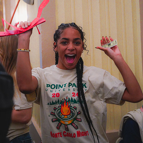 A girl holds up fake money and raffle tickets.