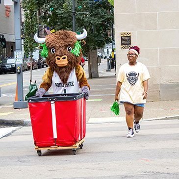 Black Diamond II and a student walk across Boulevard pushing a red bin.