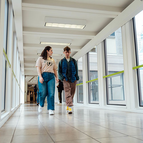 Two students walk across the skybridge.