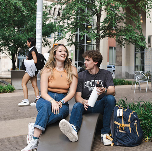 Two students share a chair in Village Park.
