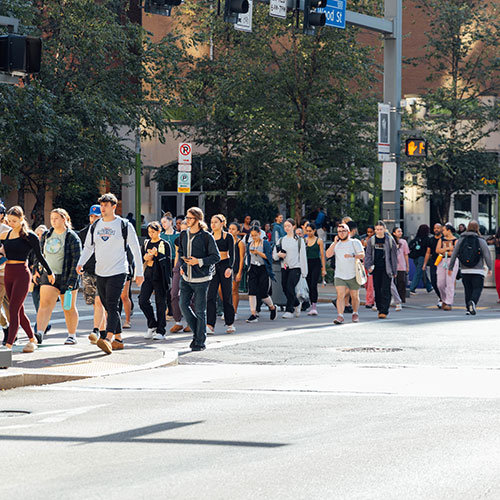 A crowd of students cross Boulevard of the Allies.