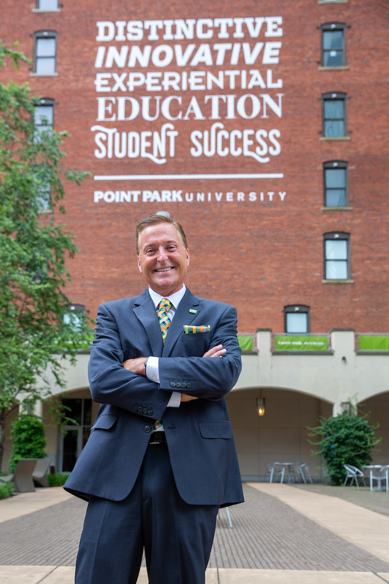President Don Green standing in front of the Distinctive, Innovative, Experiential Student Success sign outside the Boulevard Apartments