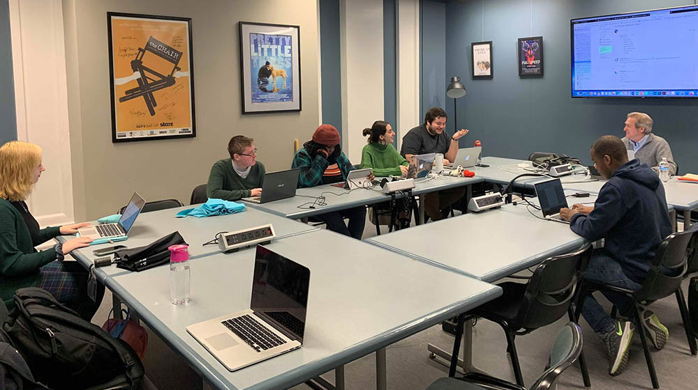 A photo of students and faculty in the writer's room on campus. 