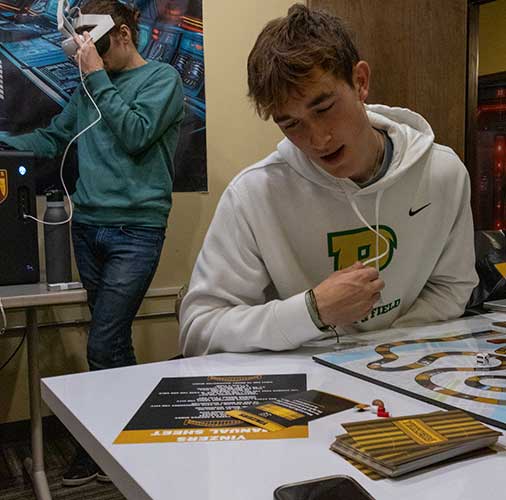 Students sit around a table playing a board game in CENT.