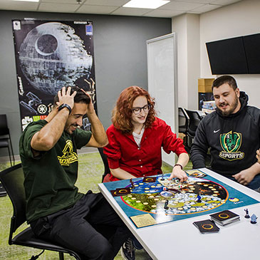 Students sit around a table playing a board game in CENT.