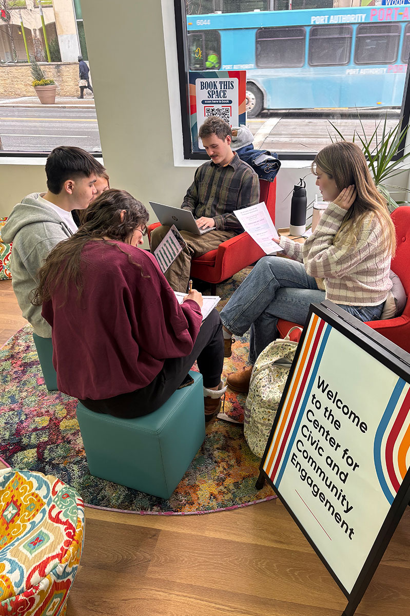 Students sit around soft seats in the front of the Center for Civic and Community Engagement.