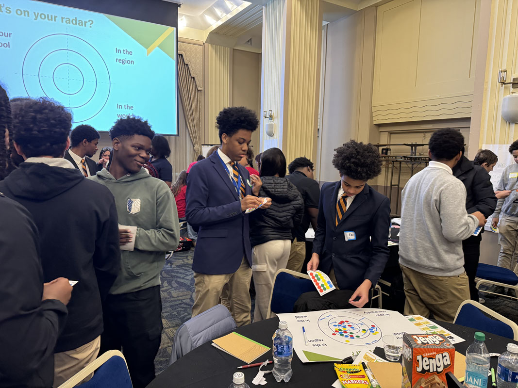 High school students stand around in the ballroom. 