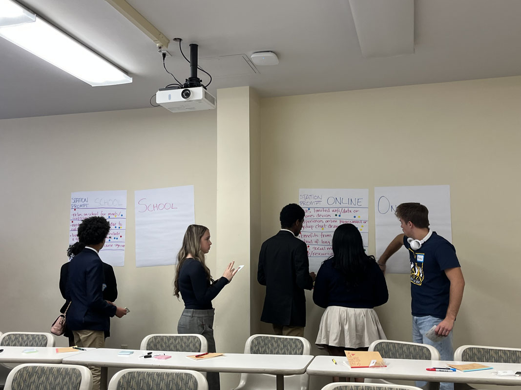Students write on large papers on the wall. 