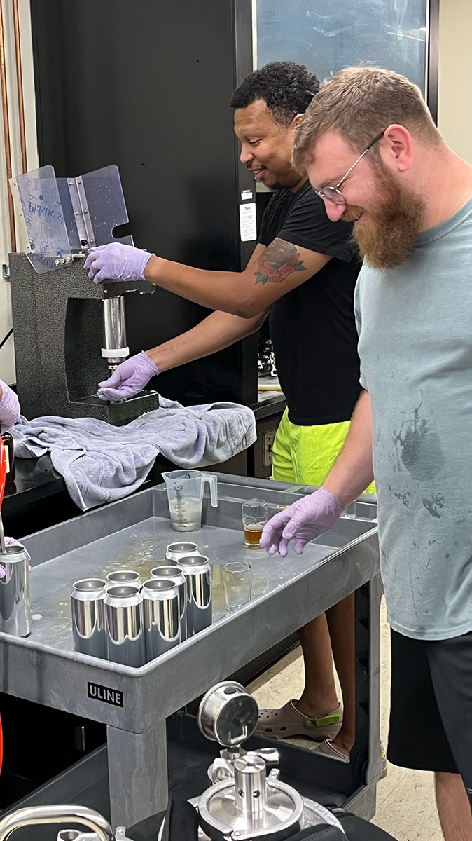 Two men fill flasks in a lab.