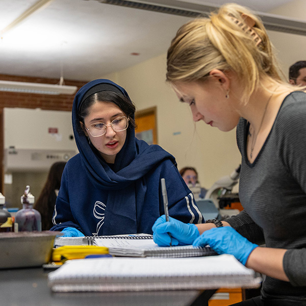 Two students take notes in a lab at Point Park University.