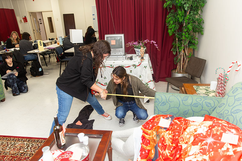 Pictured are students taking measurements in a scene in the CSI House. Photo by Randall Coleman.