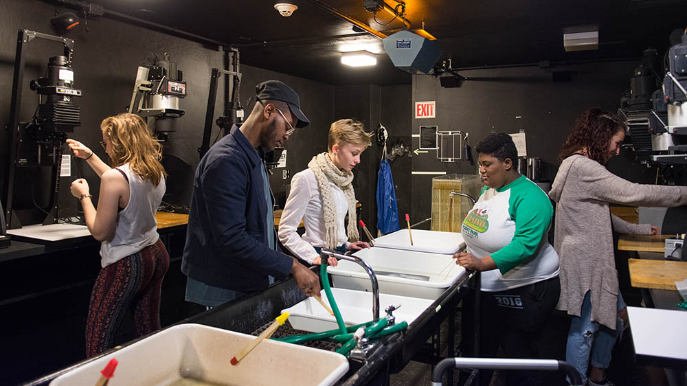 Students in the black-and-white darkroom on campus. Photo | April Friges