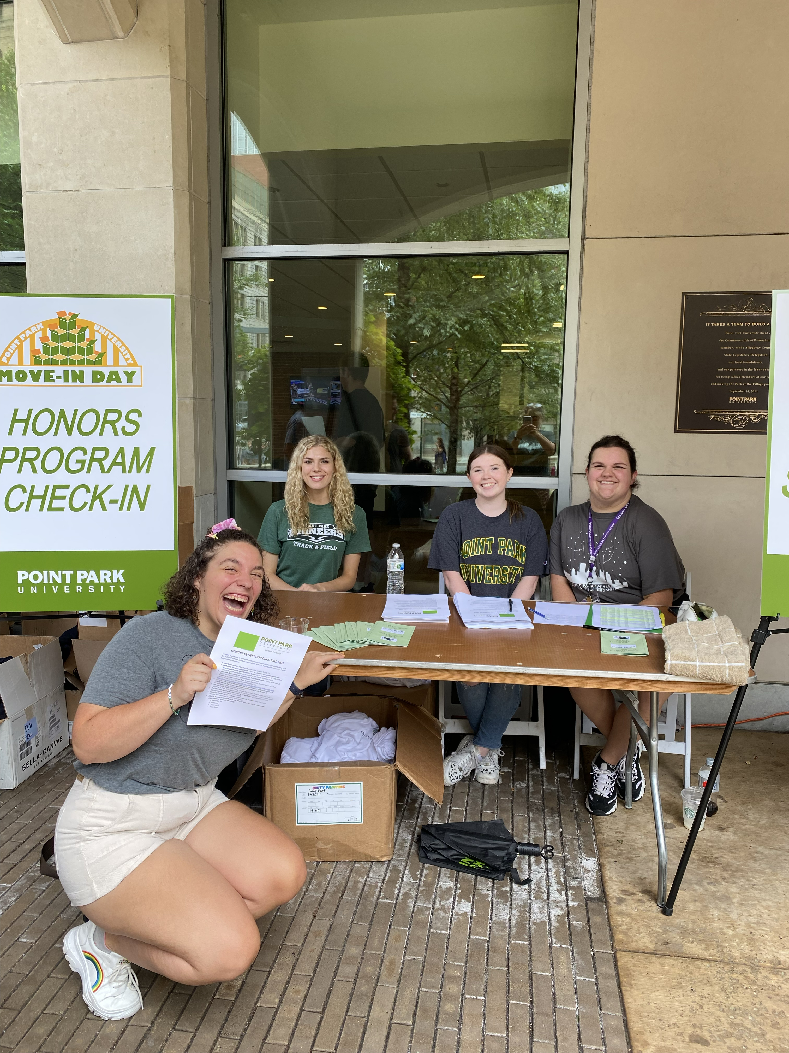 Members of the Honors Program welcome new students during Fall 2022 Welcome Weekend. They are seated at a table outside in Village Park.