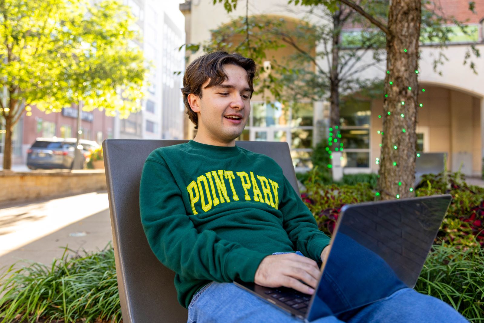 Student doing work in the courtyard wearing a Point Park sweatshirt. Photo by Paul Koontz.