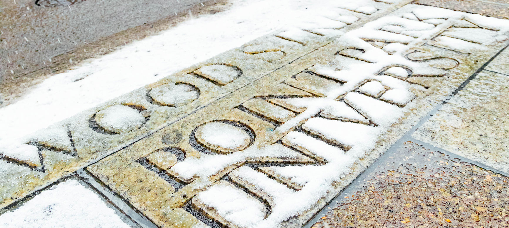 A snow-covered curb on campus that reads "Wood Street" and "Point Park University"