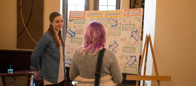 A student discusses her research poster with another student at the 2015 Humanities and Human Sciences Symposium. | Photo by Victoria A. Mikula
