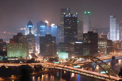 Pictured is the skyline of Downtown Pittsburgh at night with a view of the Wyndham Grand Pittsburgh Hotel.