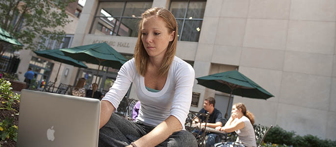 Pictured is a student using a laptop at Point Park University. 