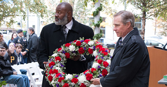 Pa. Rep. Jake Wheatley, D-Allegheny County, and Point Park President Paul Hennigan carry a red, white and blue wreath at Point Park's Veterans Day observance Nov. 11 in the Village Park. | Photo by Courtney Giles