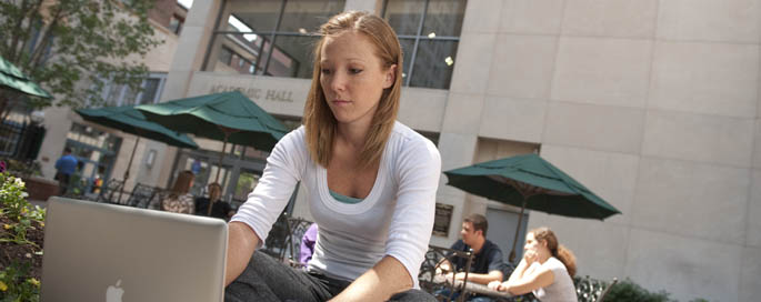 Pictured is a Point Park student working on her computer in Alumni Park.