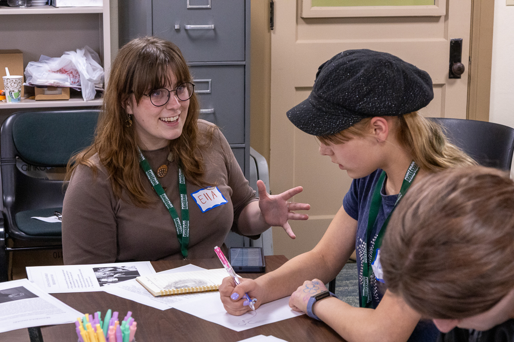 Ella Baker, one of the Creative Writing Camp's co-directors, talks to a camper as they draft a monster for their story.
