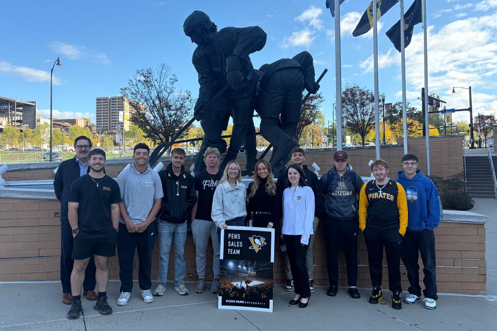 Pictured is the Pens Sales Team stadning near a statue of hockey players outside of PPG Paints Arena.