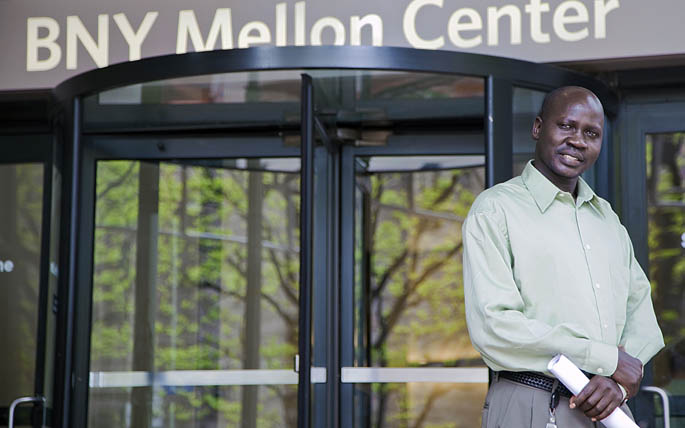 Panther Bior, accounting analyst and organizational leadership graduate student at Point Park, stands in front of the Bank of New York Mellon in Pittsburgh.