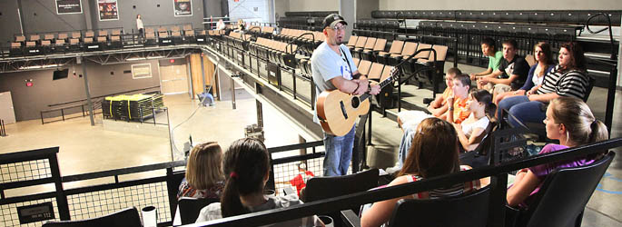 Summer workshop attendees listen to Greg Joseph of The Clarks play his bass guitar.